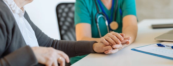 Healthcare professional holding the hands of an elder patient