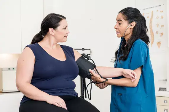A healthcare professional taking the blood pressure of a female patient