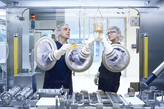 Two production specialists working with a complex manufacturing machine 